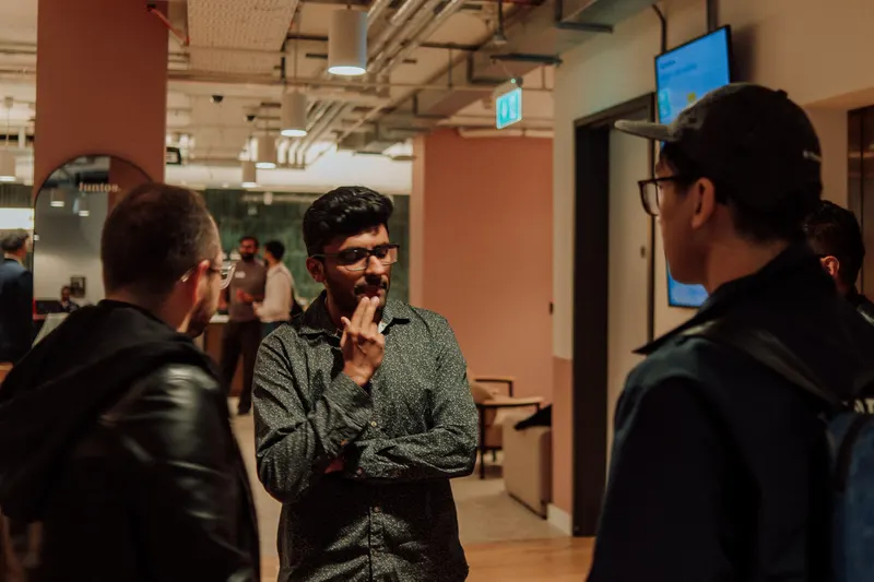 A man with a beard rests a hand on his chin while listening to another founder.