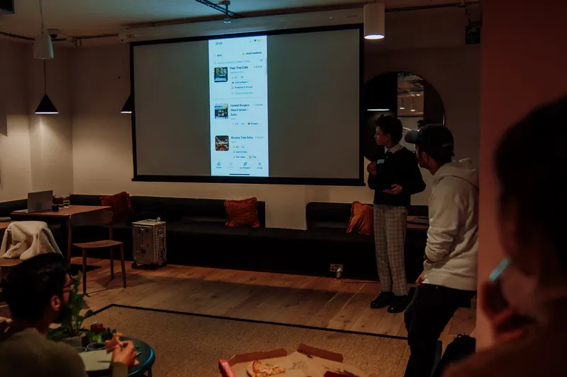 A founder presents an app on screen to the seated Growth Night audience in London.