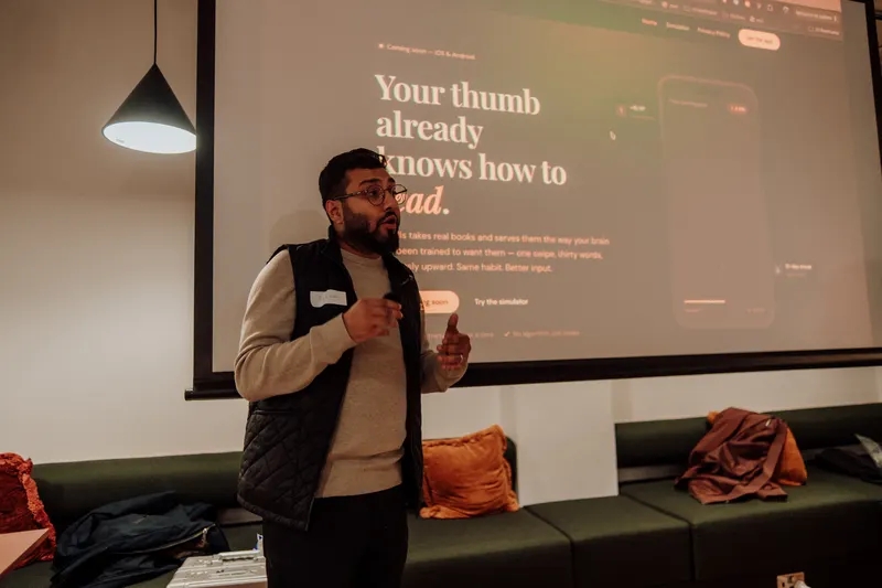 A founder presents in front of a screen showing a landing page for a reading app.