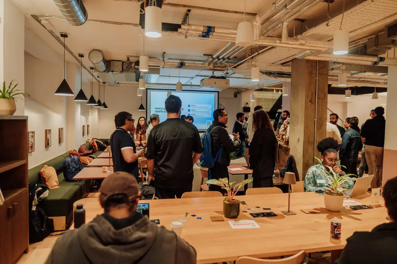 Founders gather around a long table at Growth Night while a screen glows at the back.