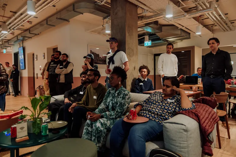 Founders sit on a sofa and stand behind it, watching a talk at Growth Night.