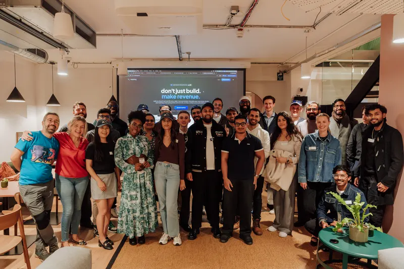 Group photo of the founders at Growth Night in the basement, smiling in front of a screen.