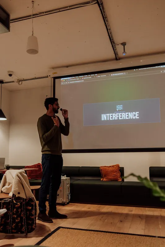 A host holds a microphone and stands next to a projected title slide at Growth Night.