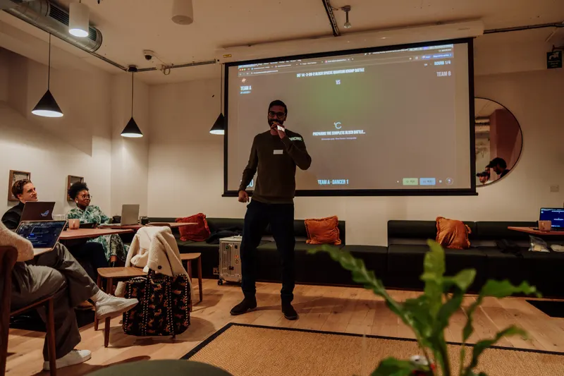 A host speaks into a microphone in front of the projected screen at Growth Night.