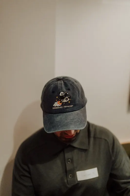 A man in a dark cap looks down with a name badge on his shirt.