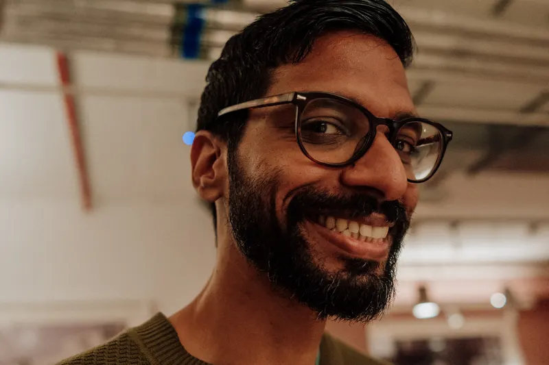 A close portrait of a smiling bearded man in glasses at Growth Night.