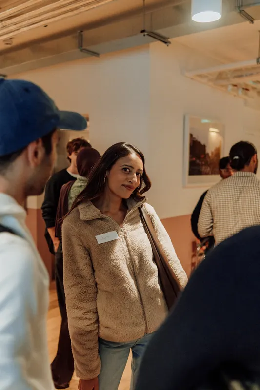 Two founders chat while a woman in a fleece smiles at Growth Night in London.