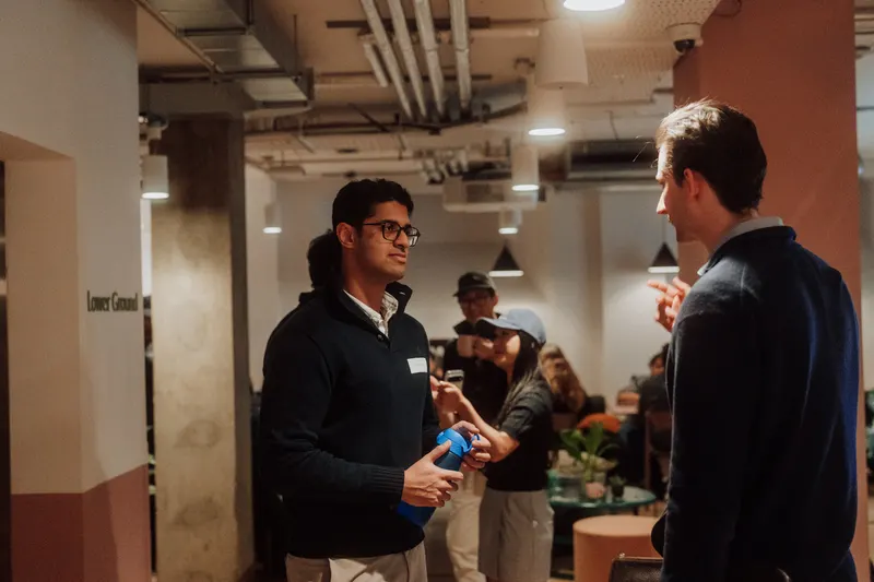 Two men in smart jumpers talk in the lower ground floor of the venue.